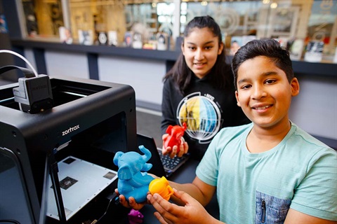 Two children hold animals printed from a 3D printer