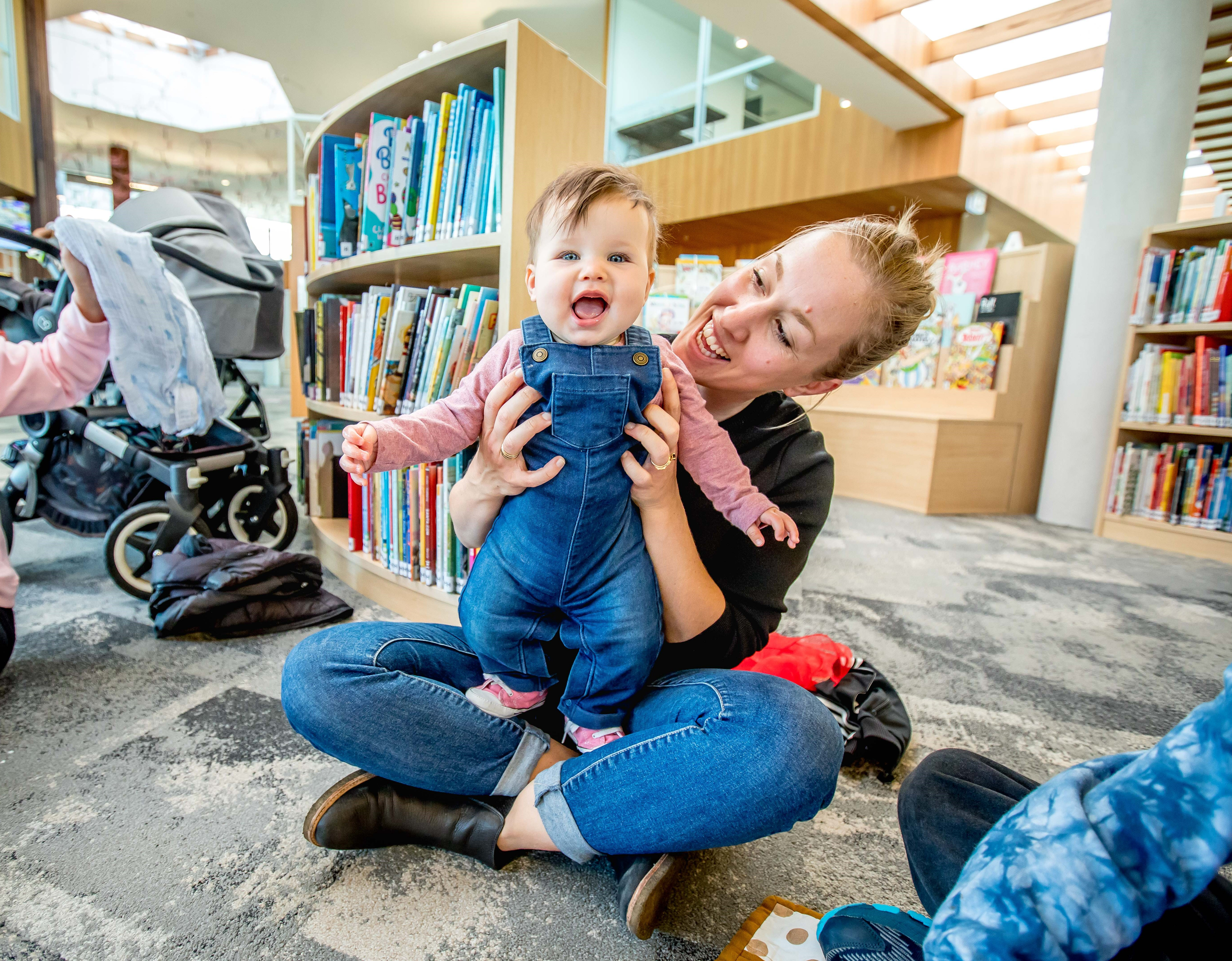 A woman holding her baby at the library.