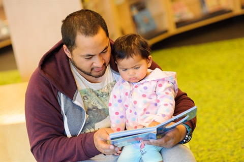 Dad reads a book to his toddler daughter